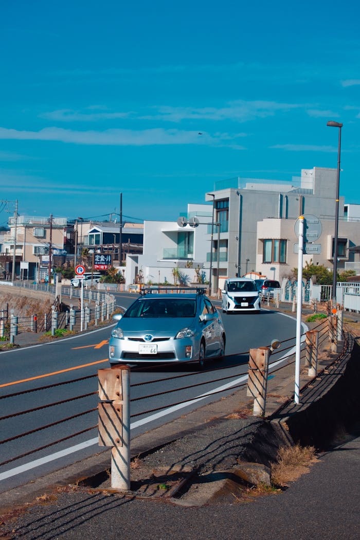 Suburban street view with cars driving under a clear blue sky in Japan.